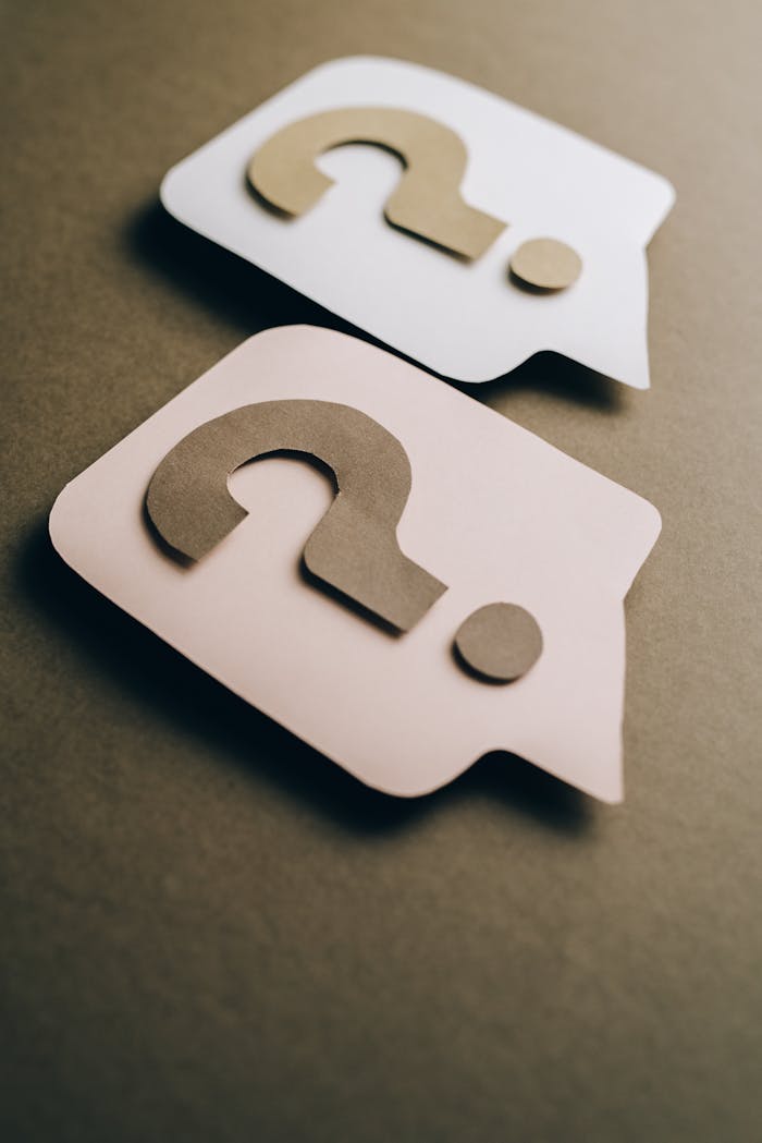 who-we-are Two paper craft question marks on speech bubbles create a conceptual visual.